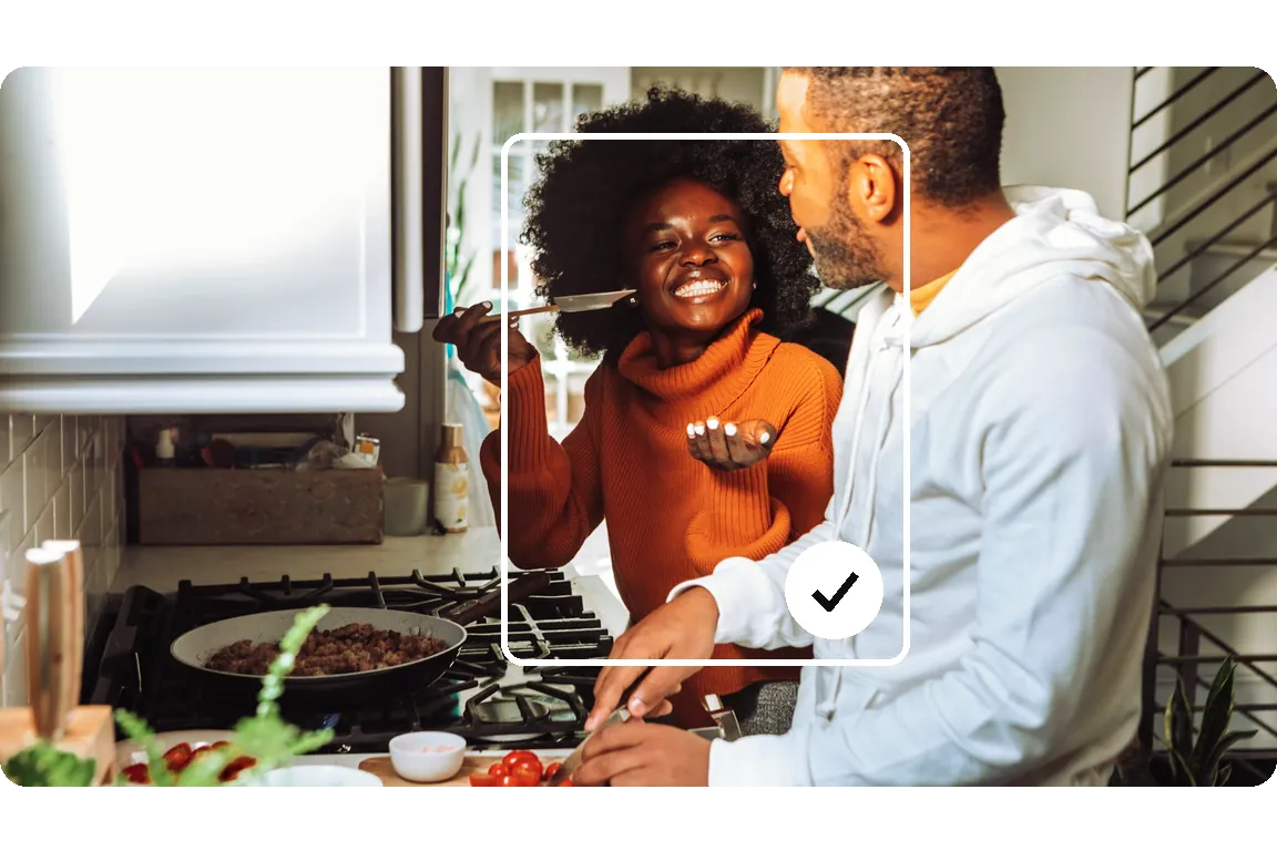 A couple laughing while cooking at home, framed in sky blue with the RESET check